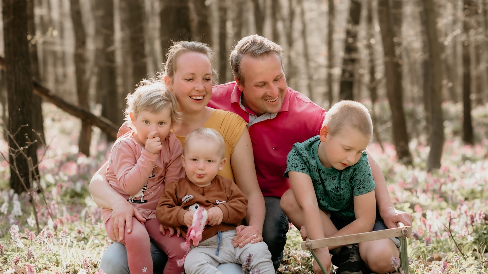 A family with three young children sitting together among wildflowers